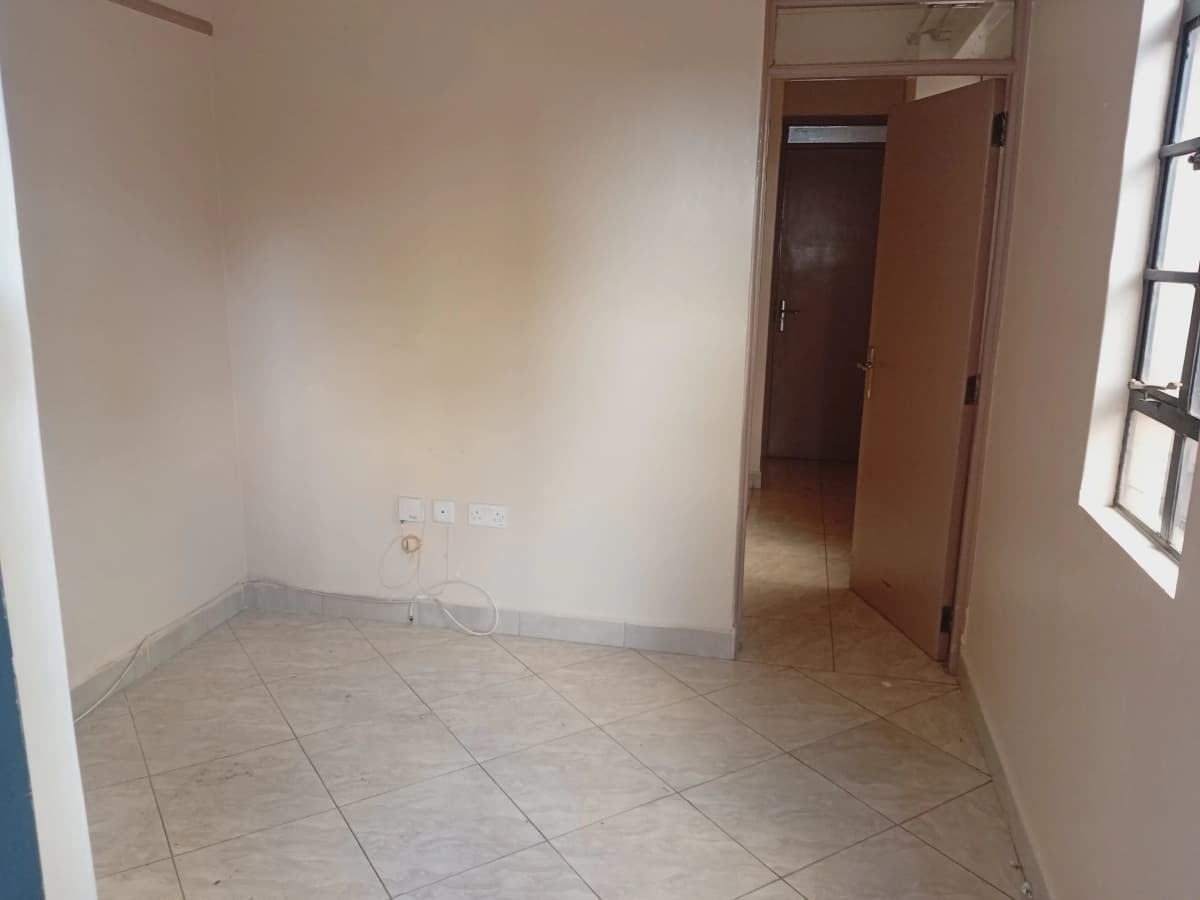 Empty bedroom with tiled floor and natural window light