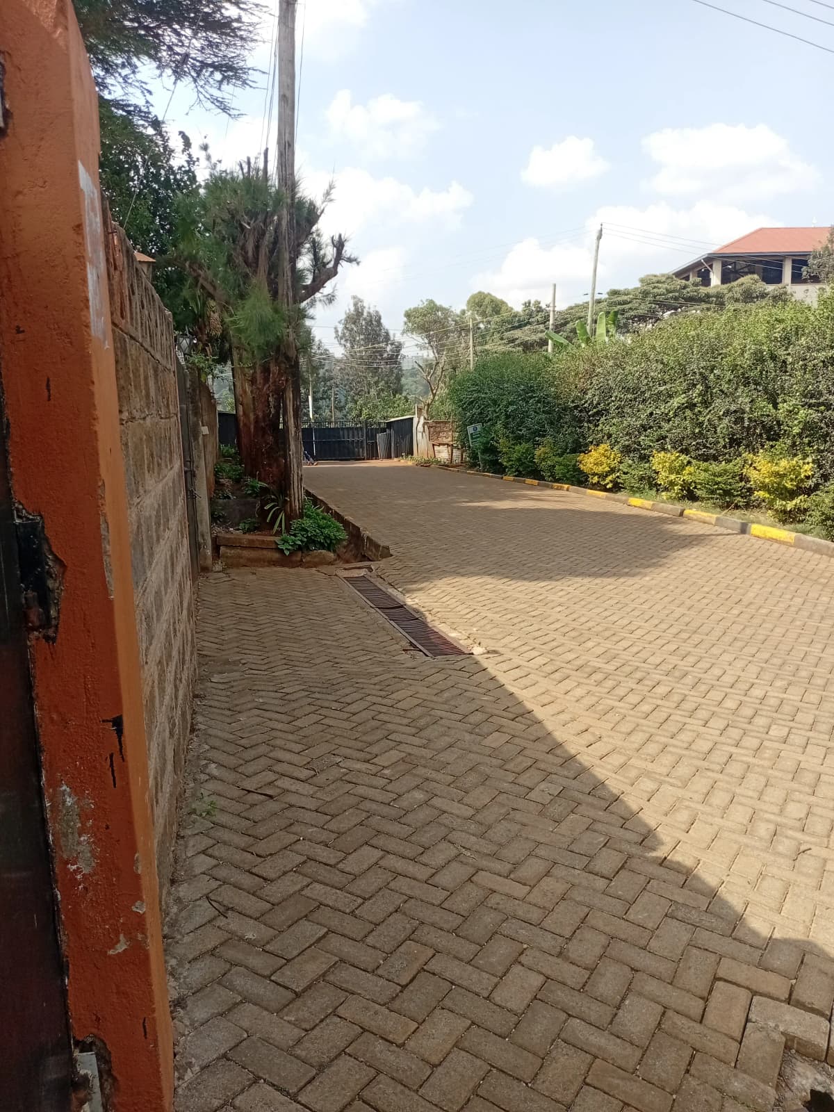 Paved compound driveway with red perimeter wall and gates