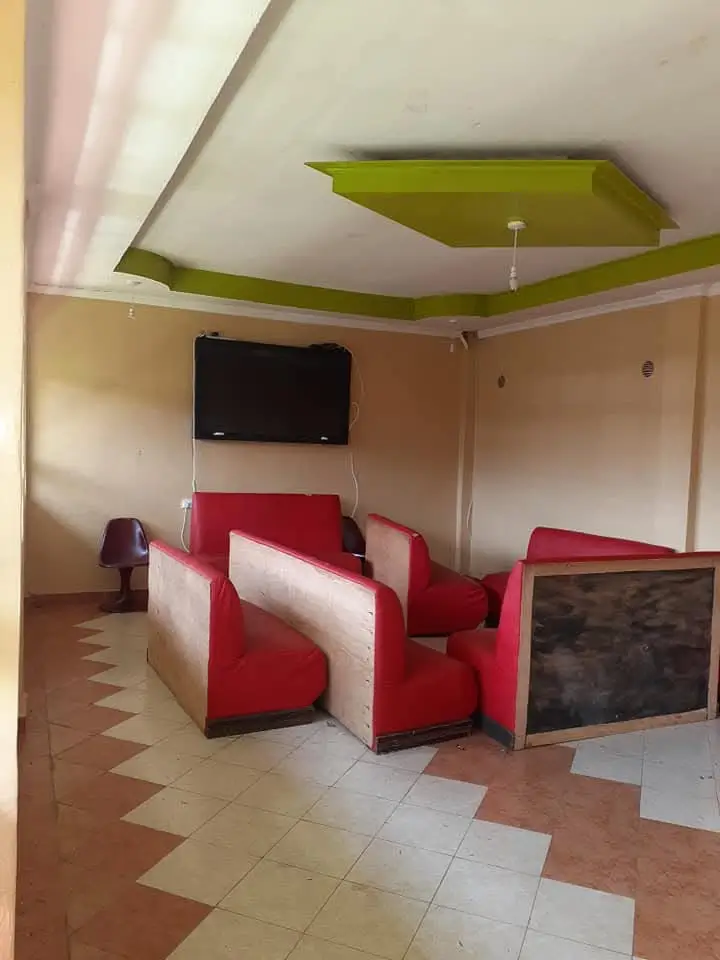Living room with red seating, wall-mounted TV, geometric ceiling