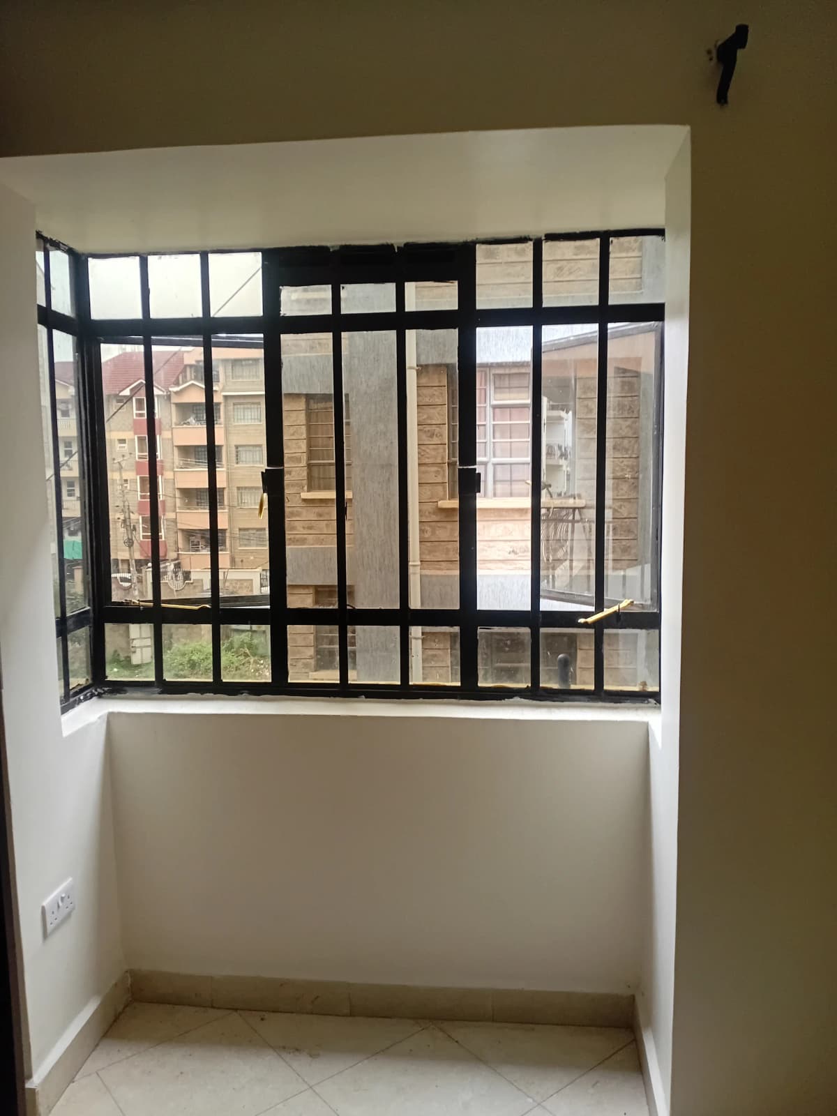 Enclosed balcony with black security grill and city views