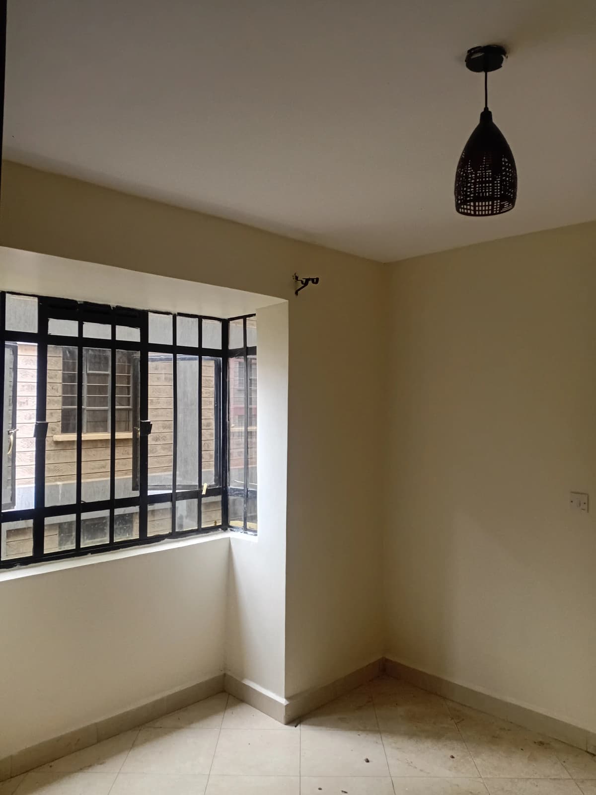 Minimal bedroom with barred window and pendant light fixture