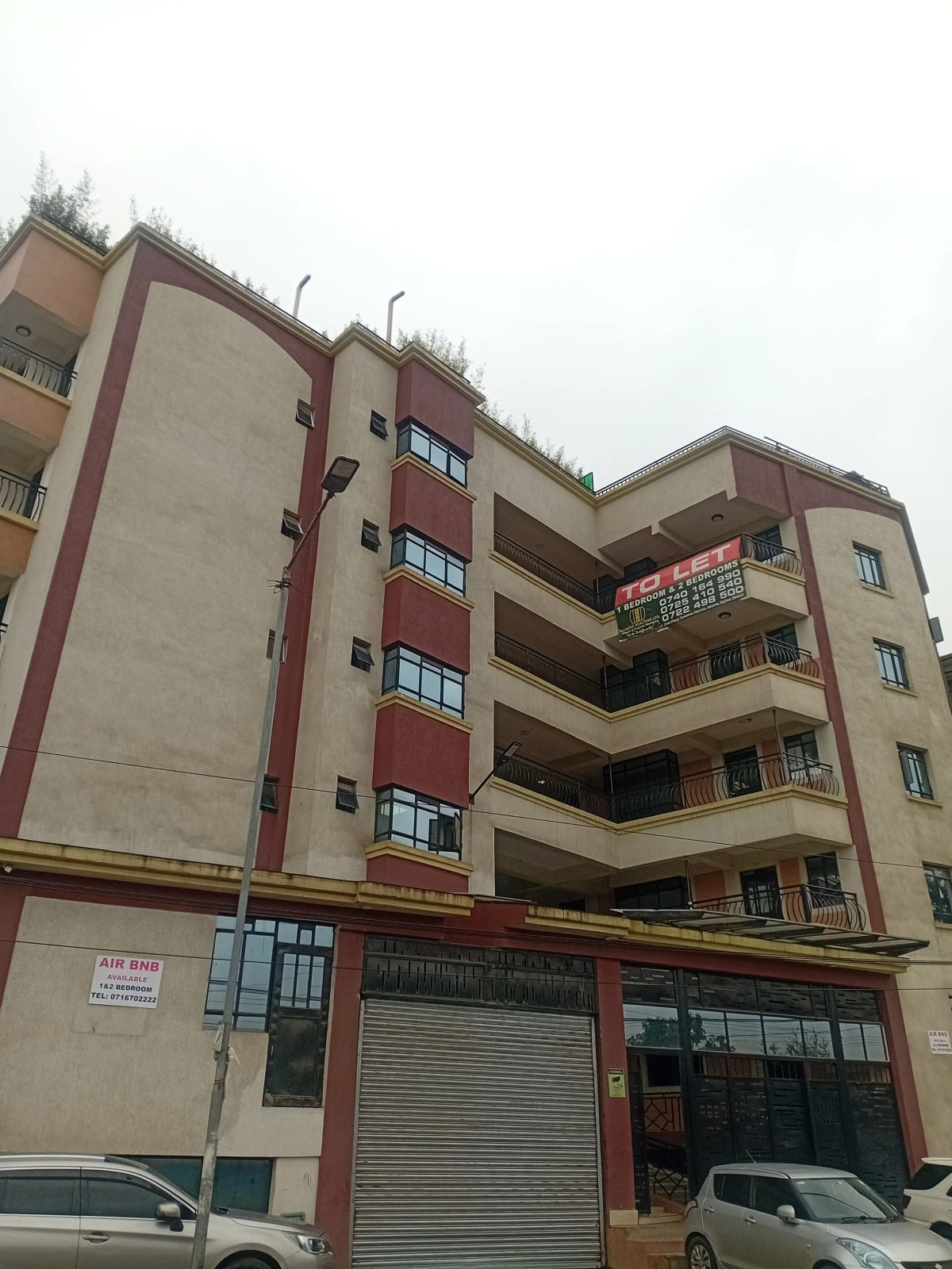 Multi-story residential apartment building with red and beige facade