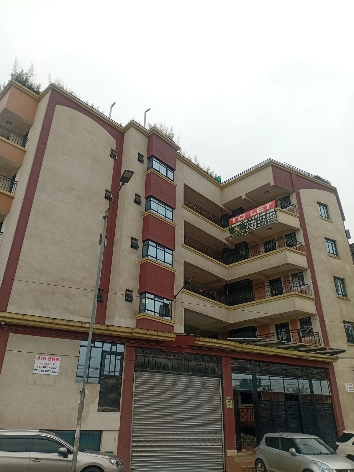 Multi-story residential apartment building with red and beige facade