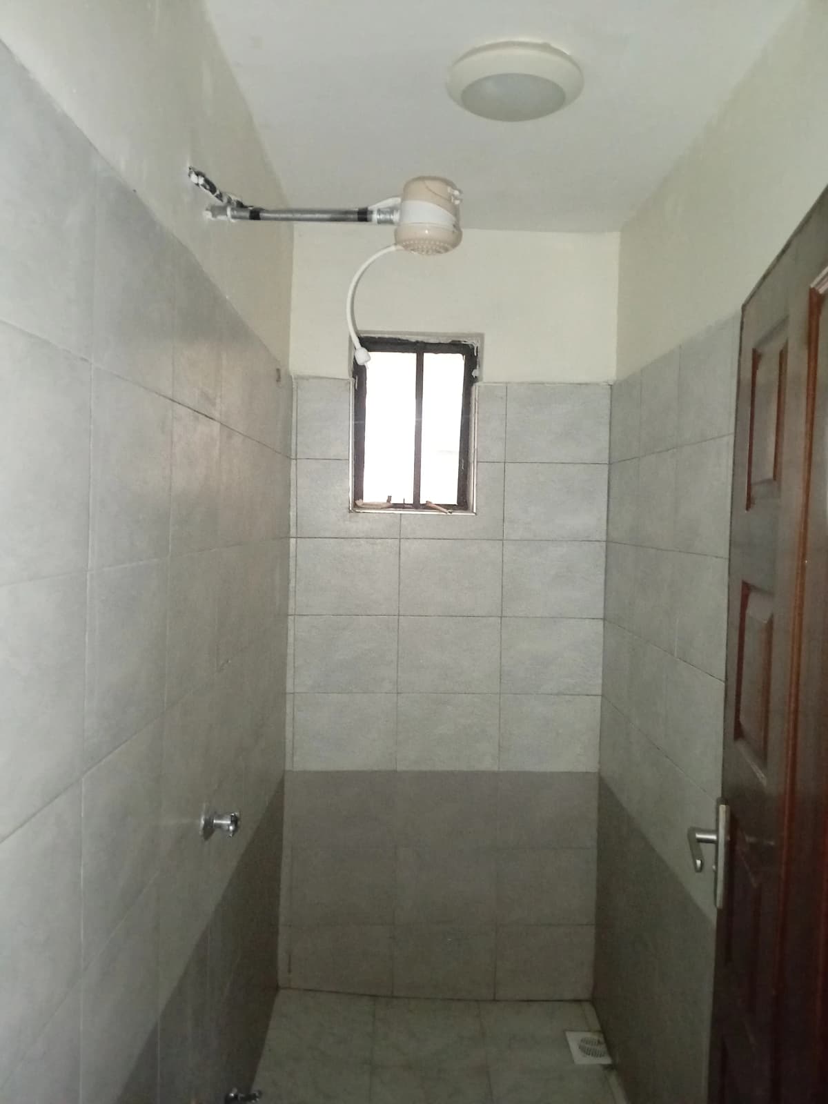 Simple bathroom with tiled walls and overhead shower fixture