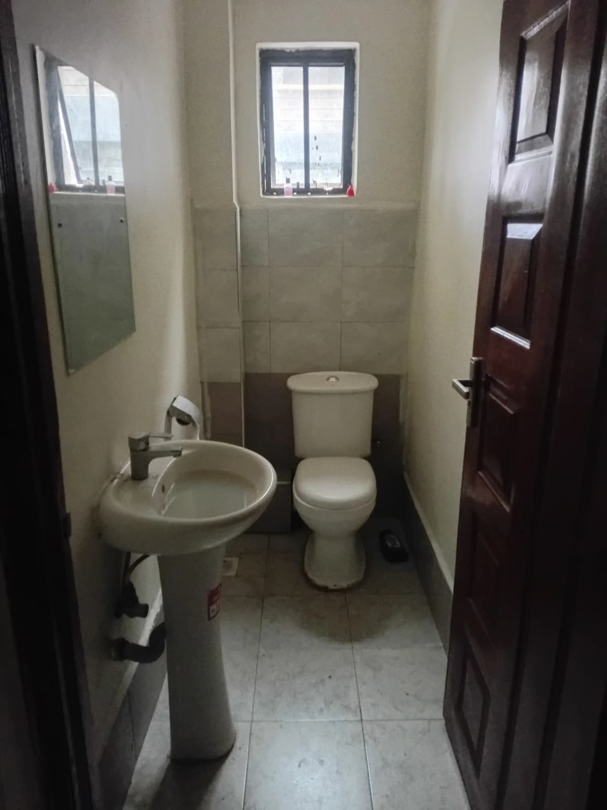 Compact bathroom with pedestal sink, toilet, and window
