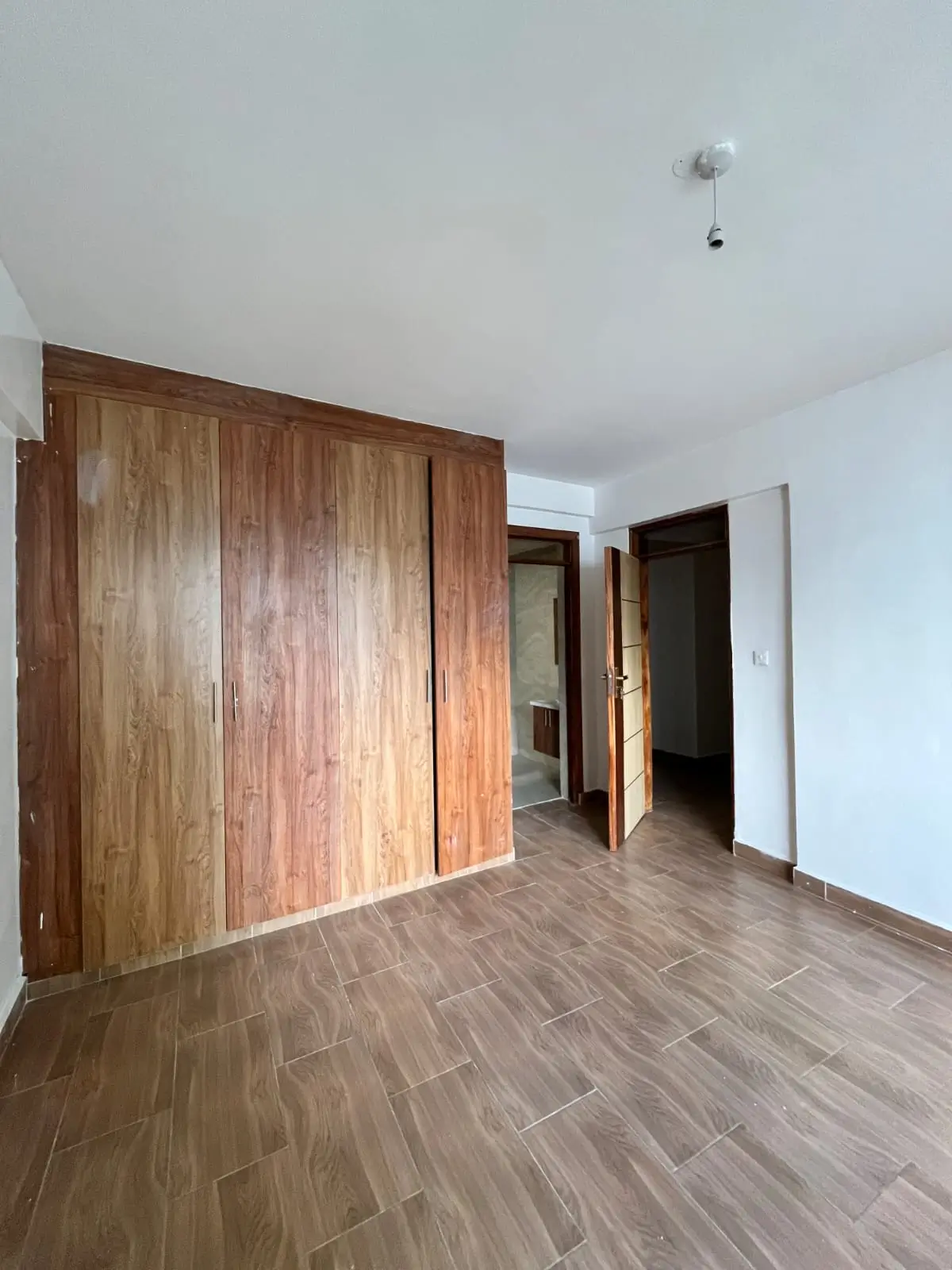 Spacious bedroom with wooden wardrobe and herringbone flooring