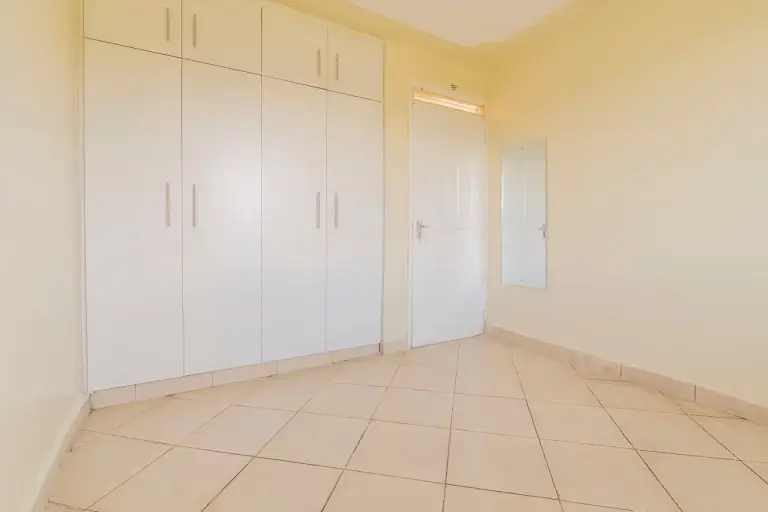 Spacious bedroom with built-in white wardrobes and tiled flooring
