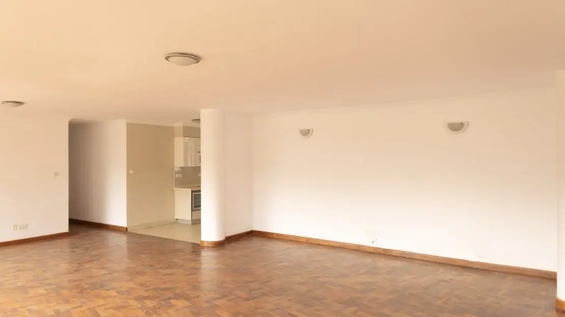 Open-plan living space with wooden flooring and kitchen entrance