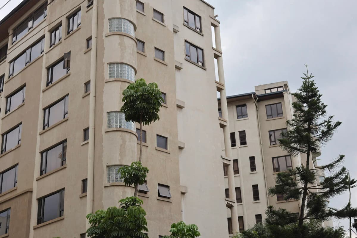 Beige apartment building facade with balconies and landscaping