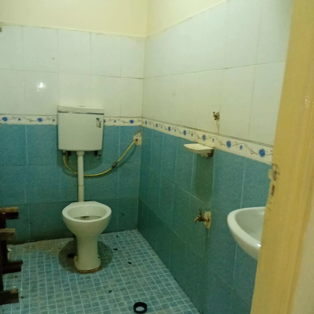 Basic bathroom with turquoise tiles, pedestal toilet, sink