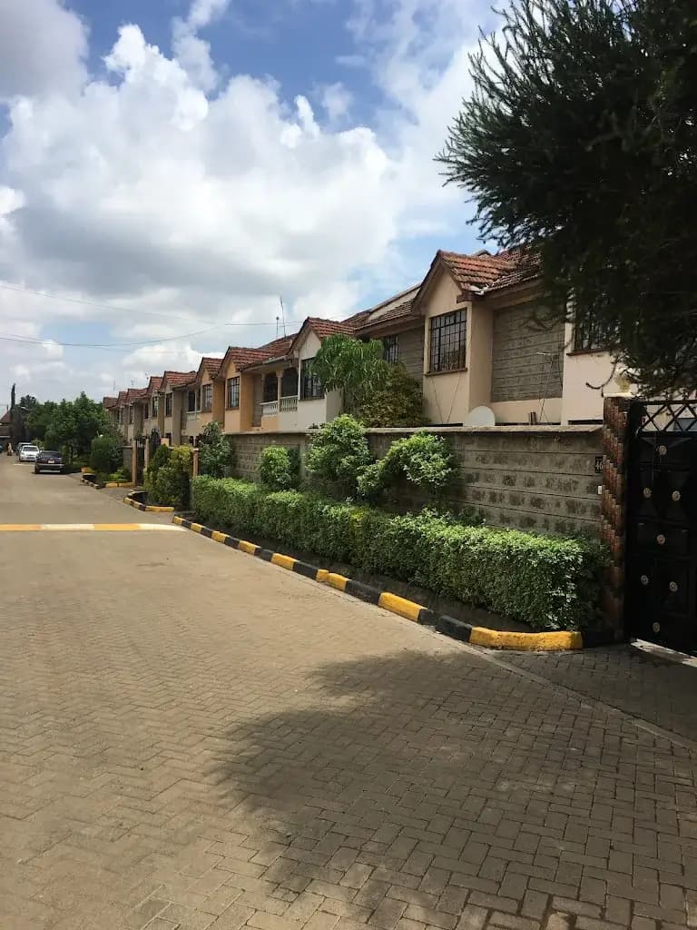 Residential compound with manicured hedges and paved driveway