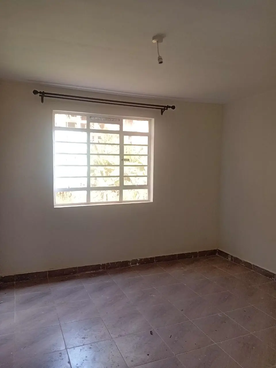 Empty bedroom with barred window and tile flooring