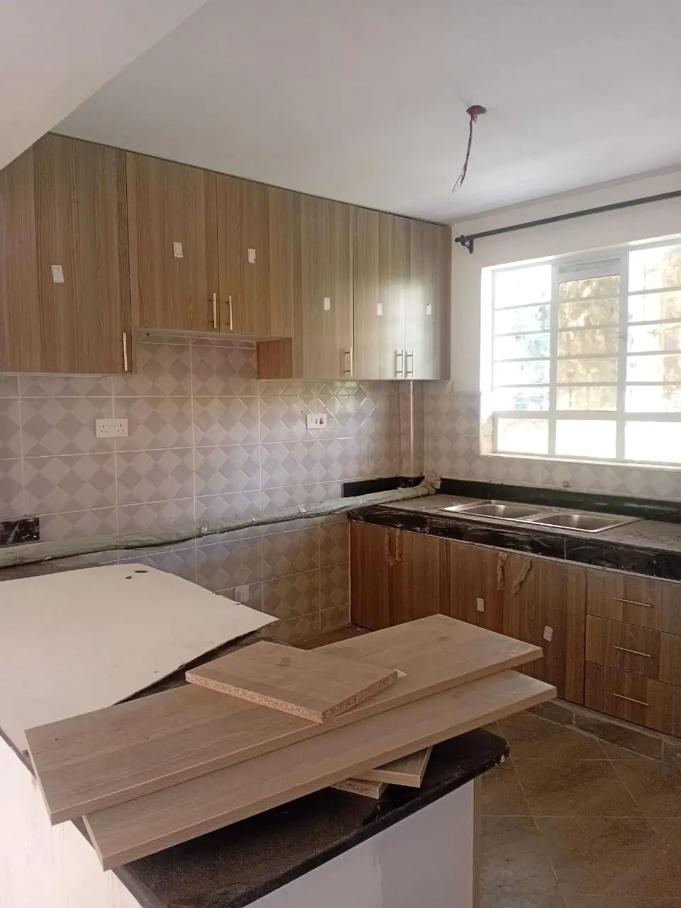 Modern kitchen with wooden cabinetry and tiled backsplash under construction