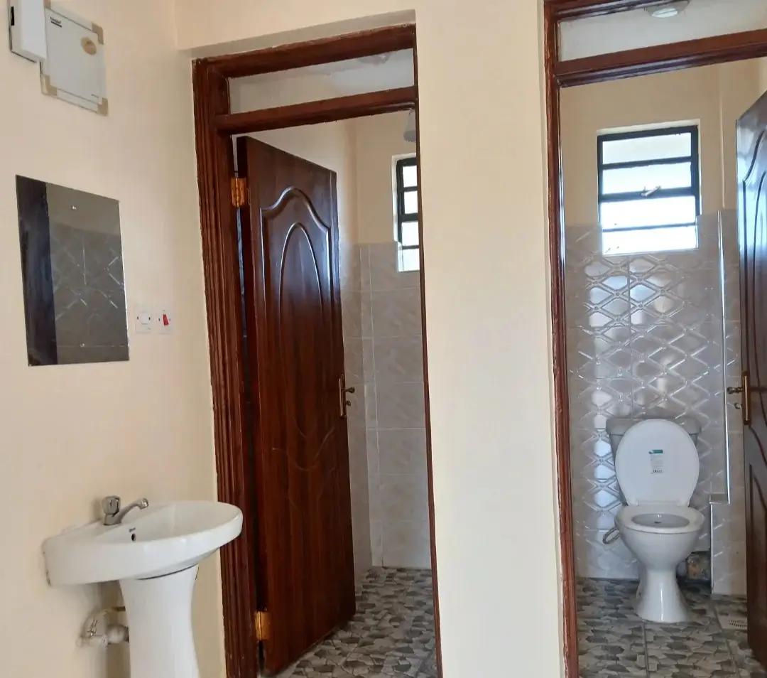 Dual bathroom setup with pedestal sink and toilet compartments