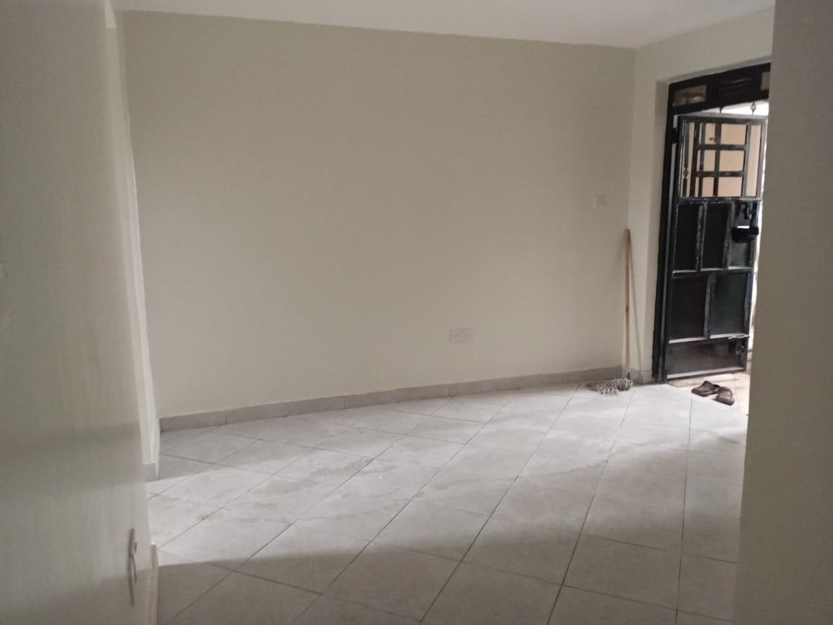Empty living room with tiled flooring and black entrance door