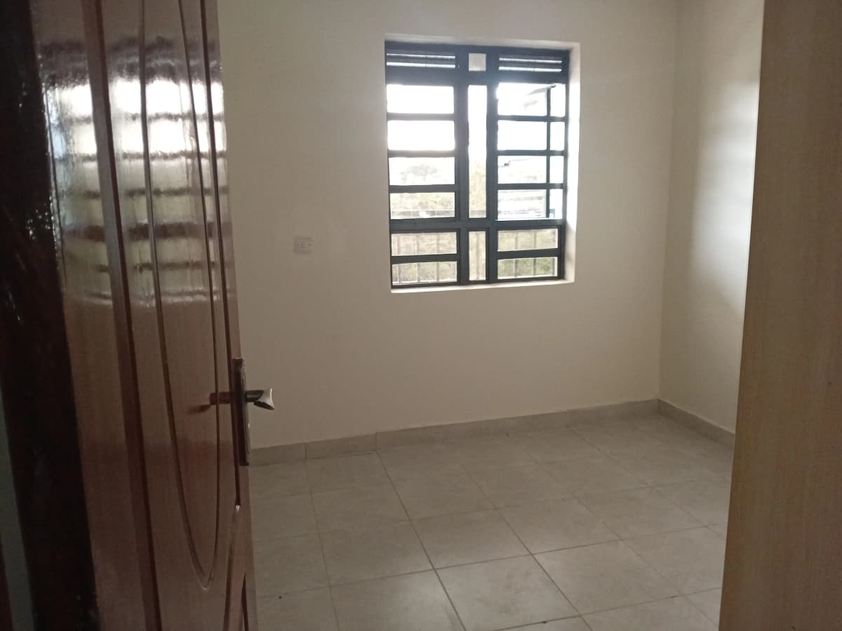 Empty bedroom with tiled floor, window, and wooden door