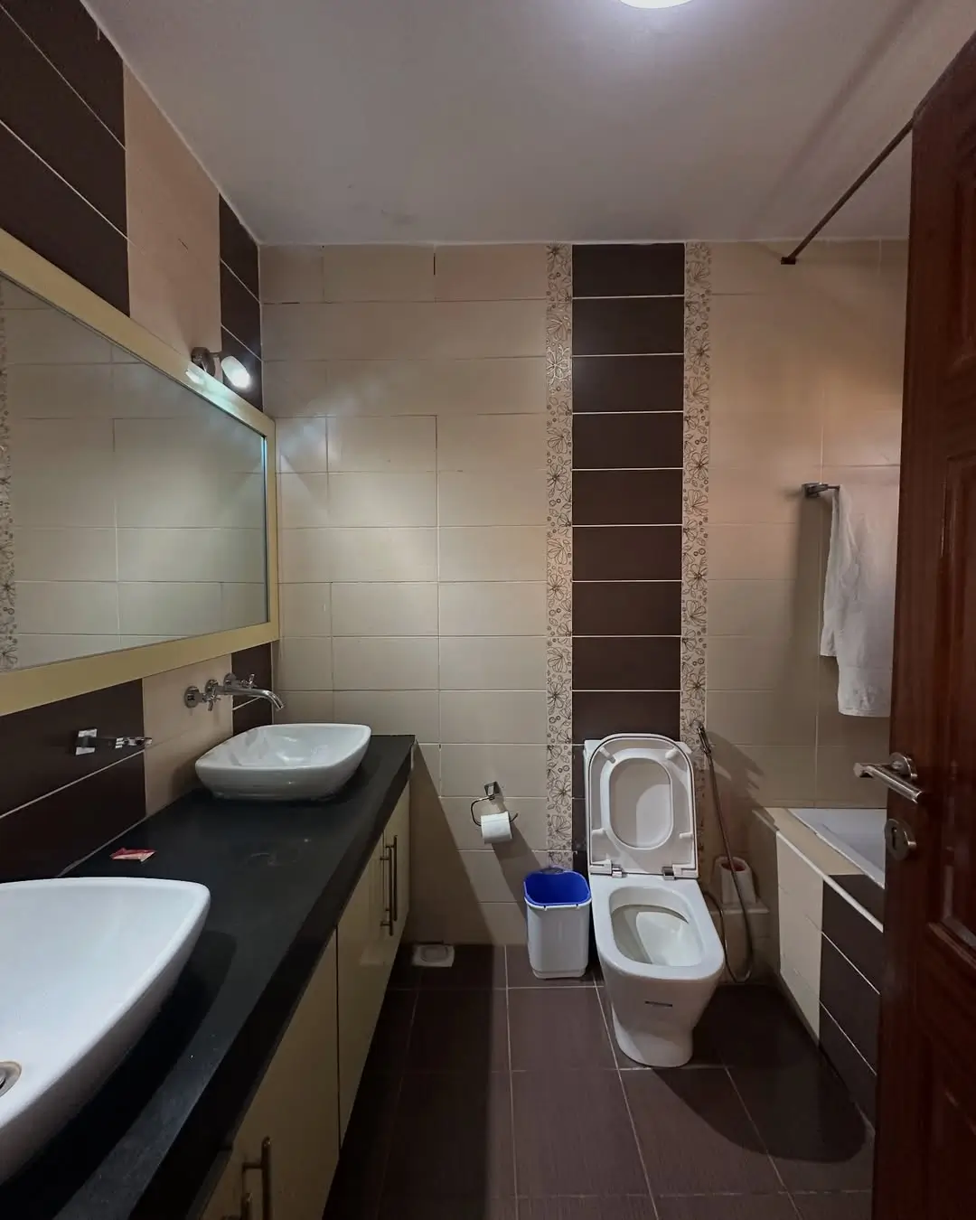 Modern bathroom with dual sinks, toilet, and tiled walls