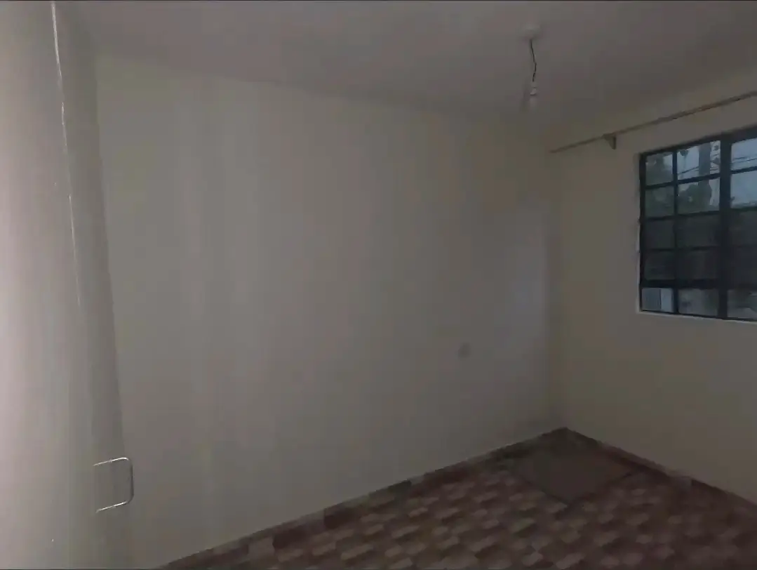 Empty bedroom with window and bare tiled floor