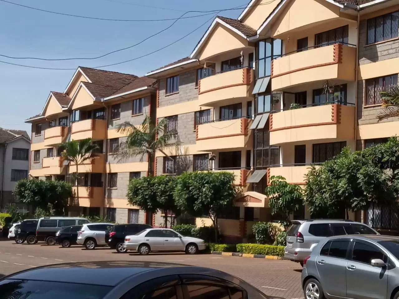 Multi-story residential apartment building with cream facade and landscaping