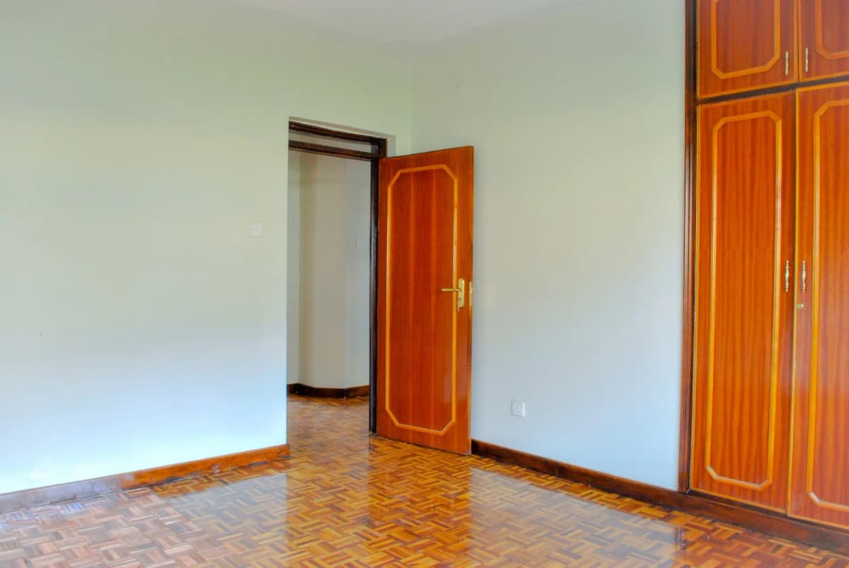 Spacious bedroom with herringbone wooden floor and wardrobes