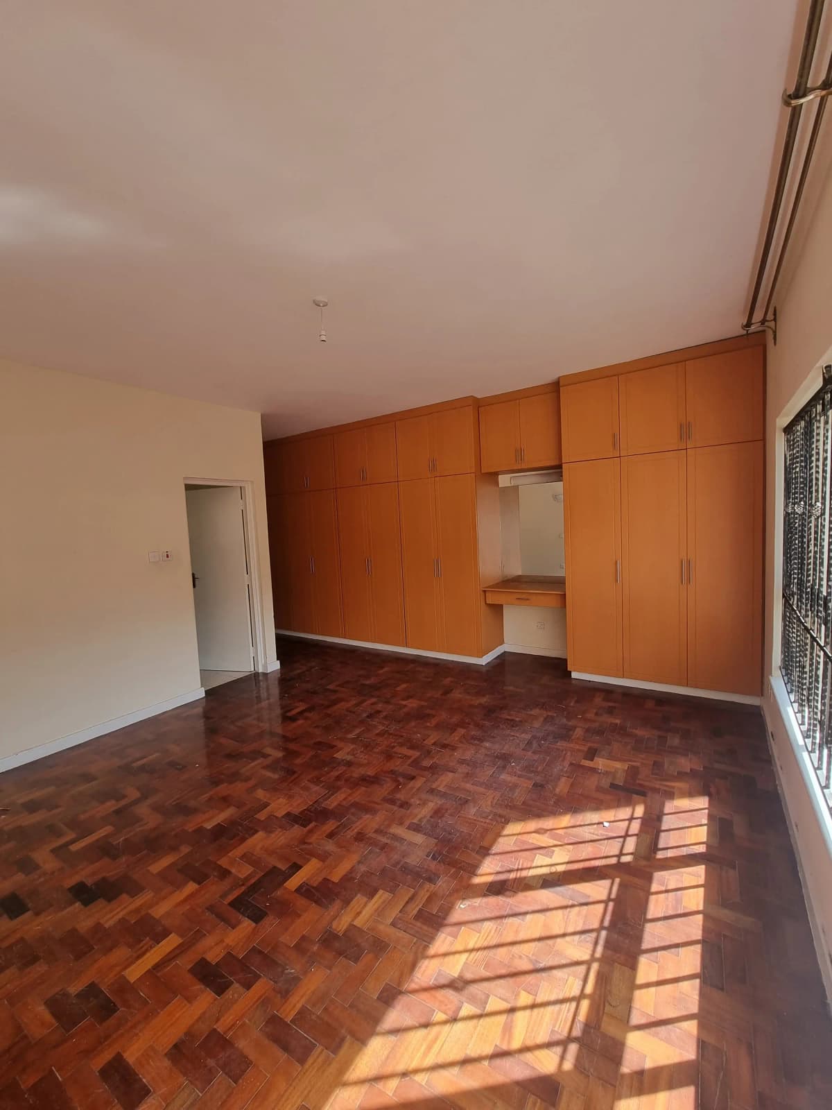 Spacious bedroom with wooden herringbone floors and built-in wardrobes