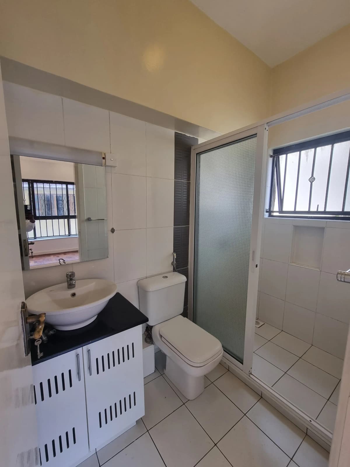 Compact bathroom with sink, toilet, shower enclosure, mirror