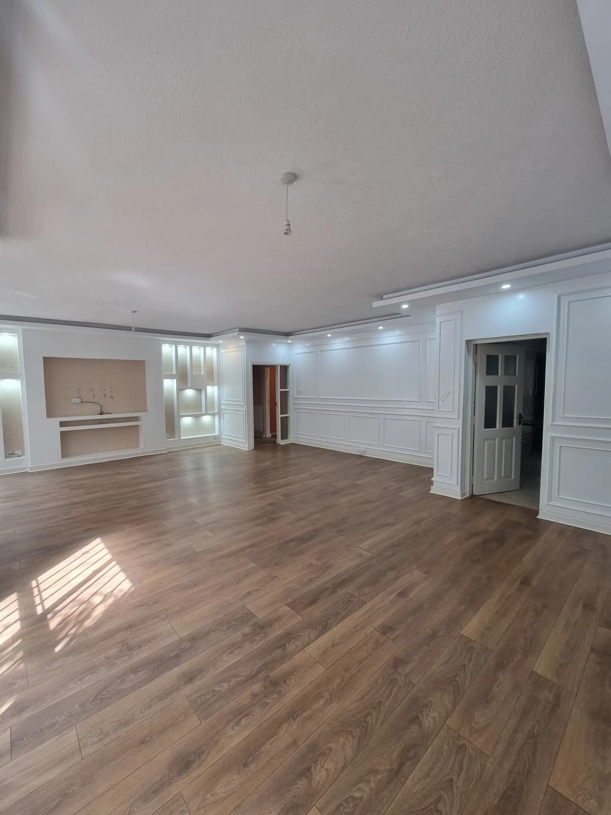 Spacious open-plan living area with wooden flooring and bright lighting