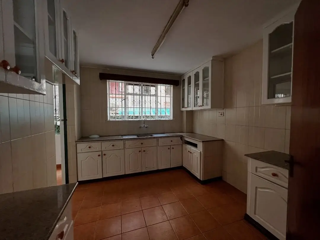 Spacious kitchen with cream cabinetry and terracotta tile flooring