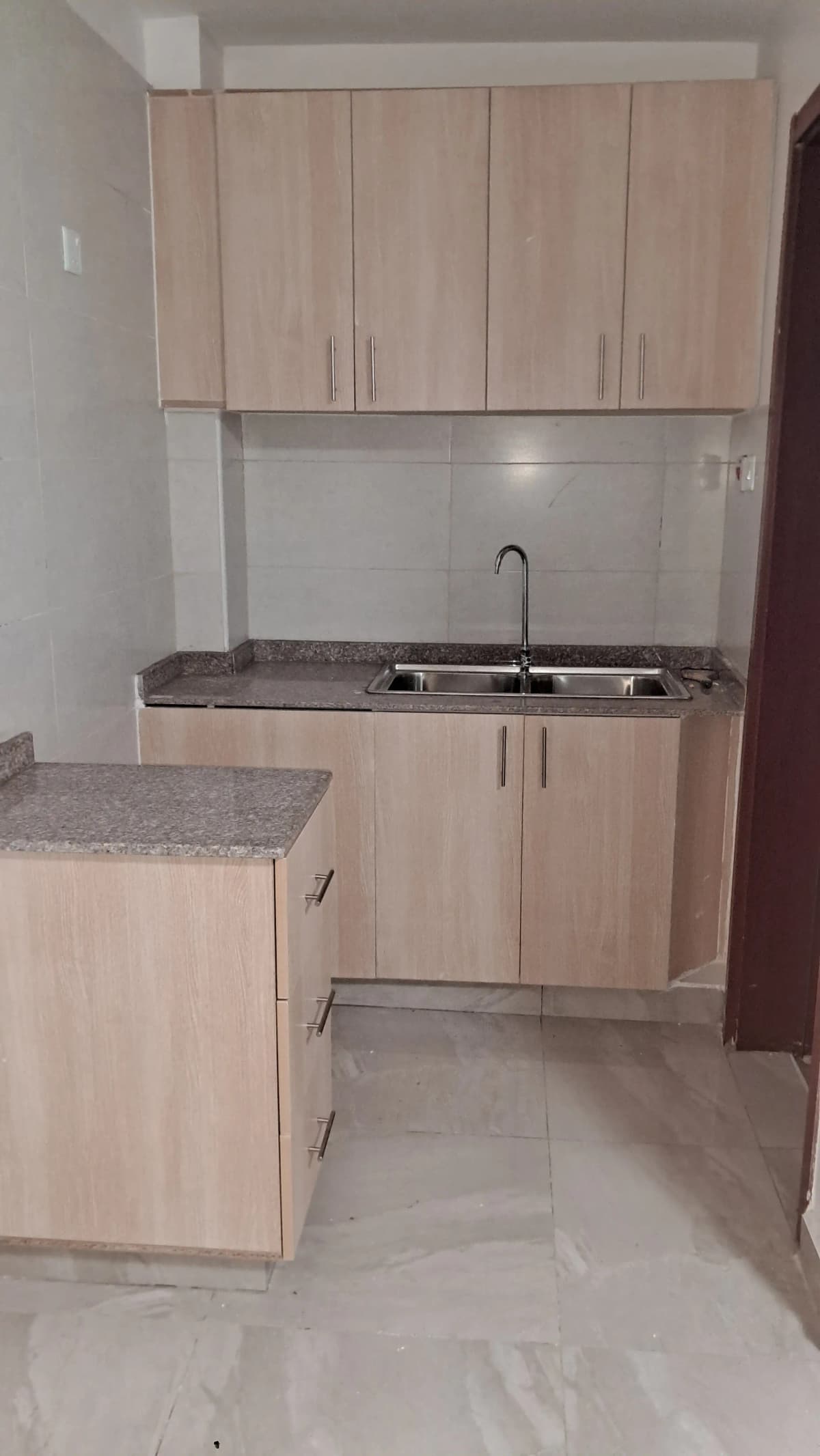Compact kitchen with light wood cabinets and granite countertop