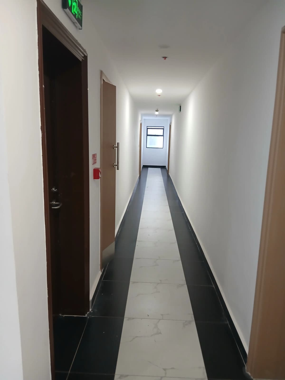 Clean modern corridor with dark stripe flooring and exit sign