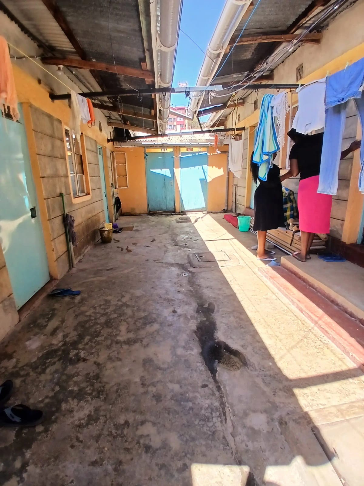 Narrow outdoor alley with makeshift structures and clotheslines