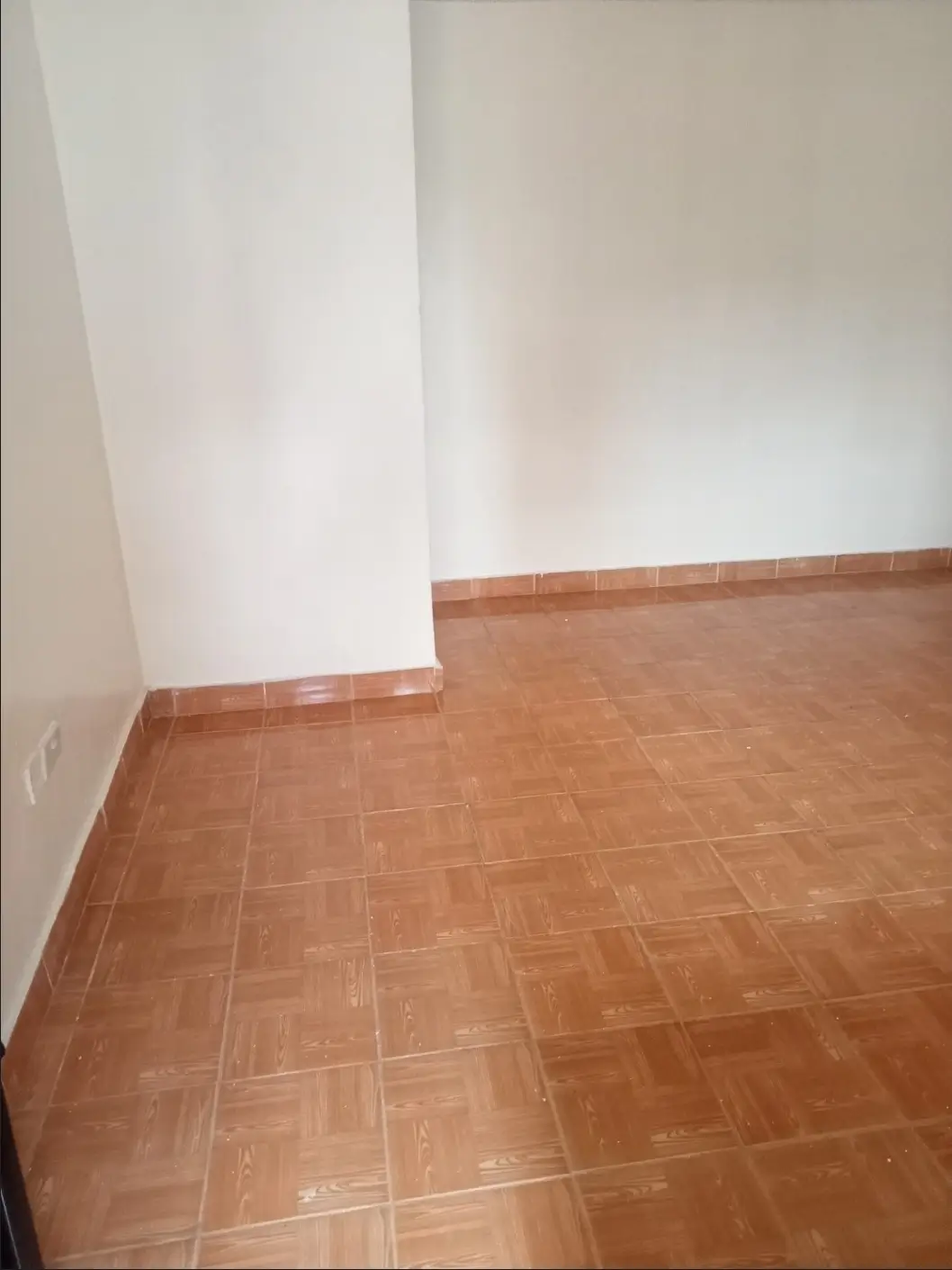 Empty bedroom with terracotta tile flooring and white walls