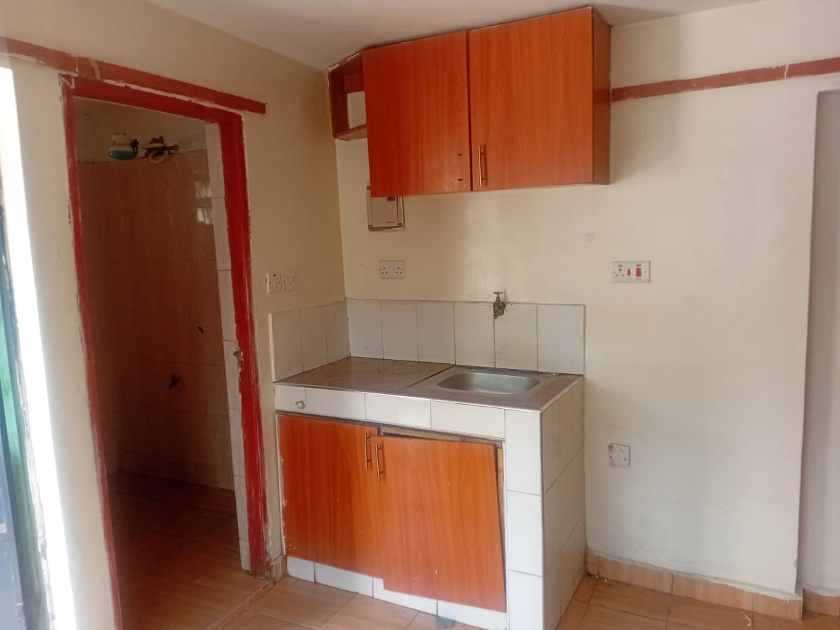 Compact kitchen with red cabinetry and stainless steel sink