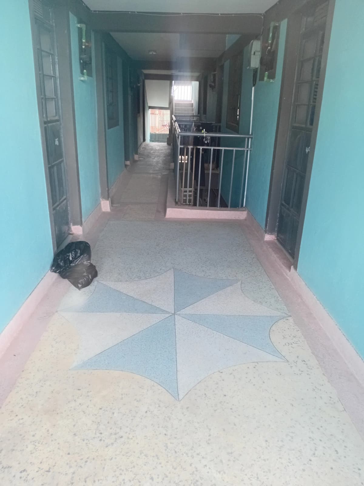 Long corridor with turquoise walls and geometric floor pattern