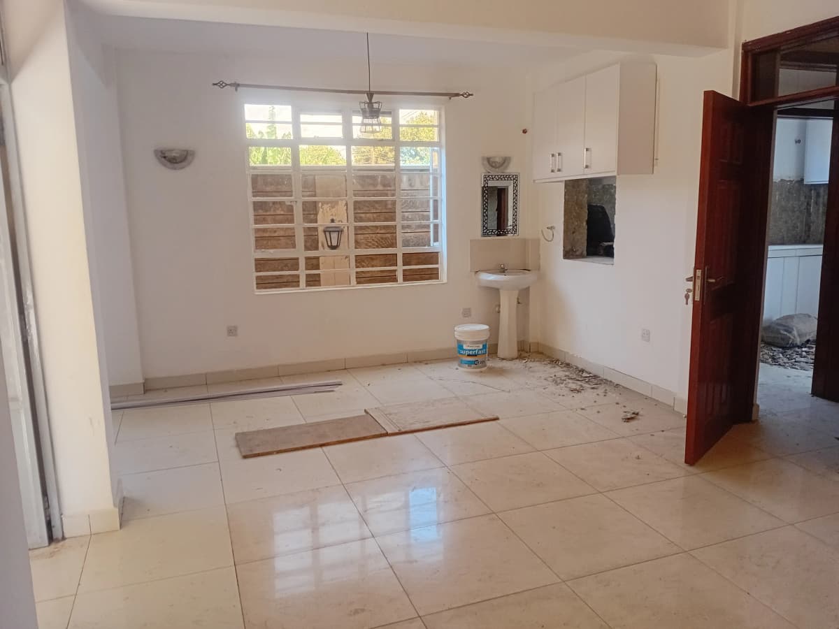 Spacious open-plan living area with kitchen visible, bright natural light