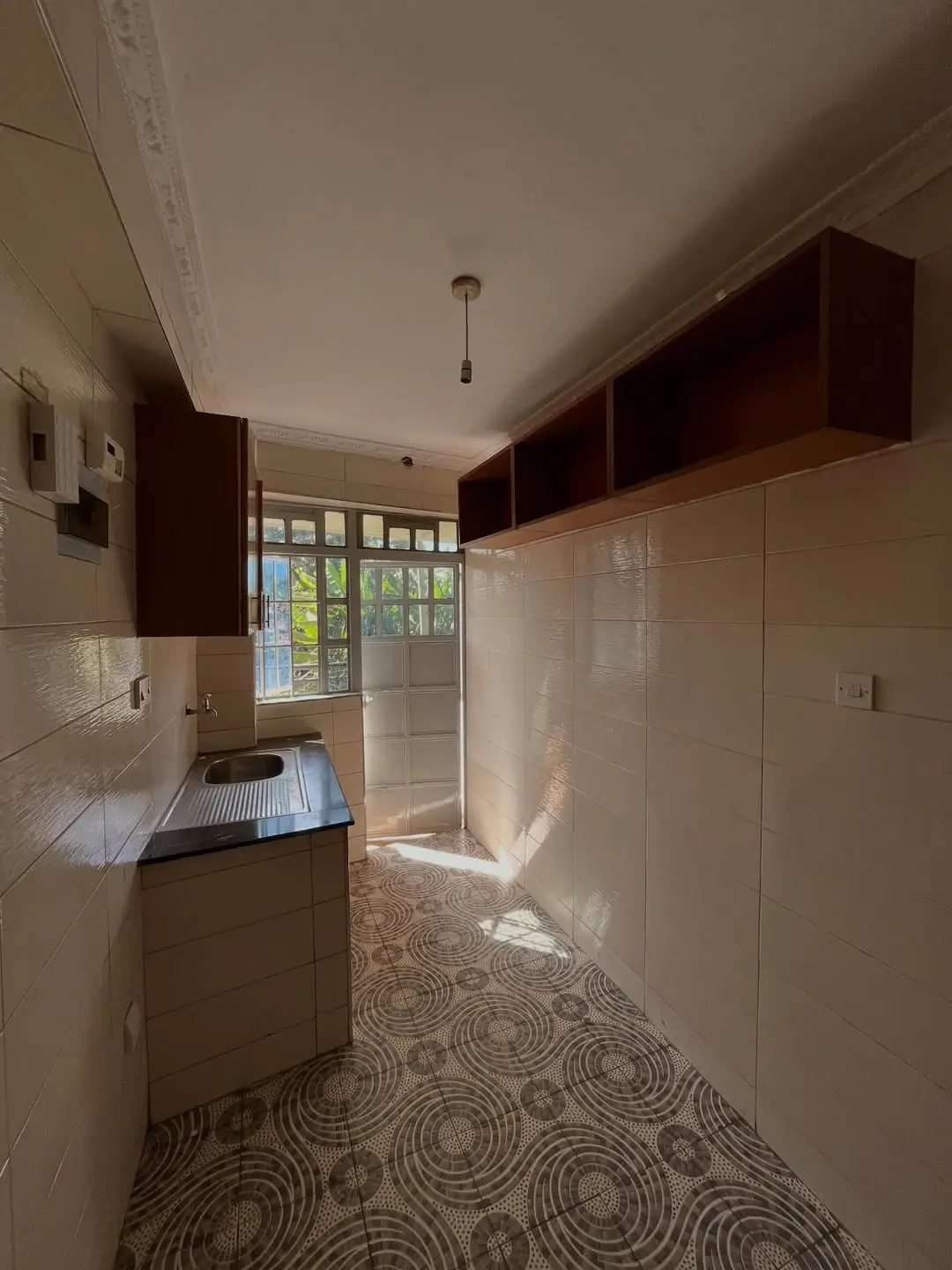 Galley kitchen with dark cabinetry and geometric floor tile