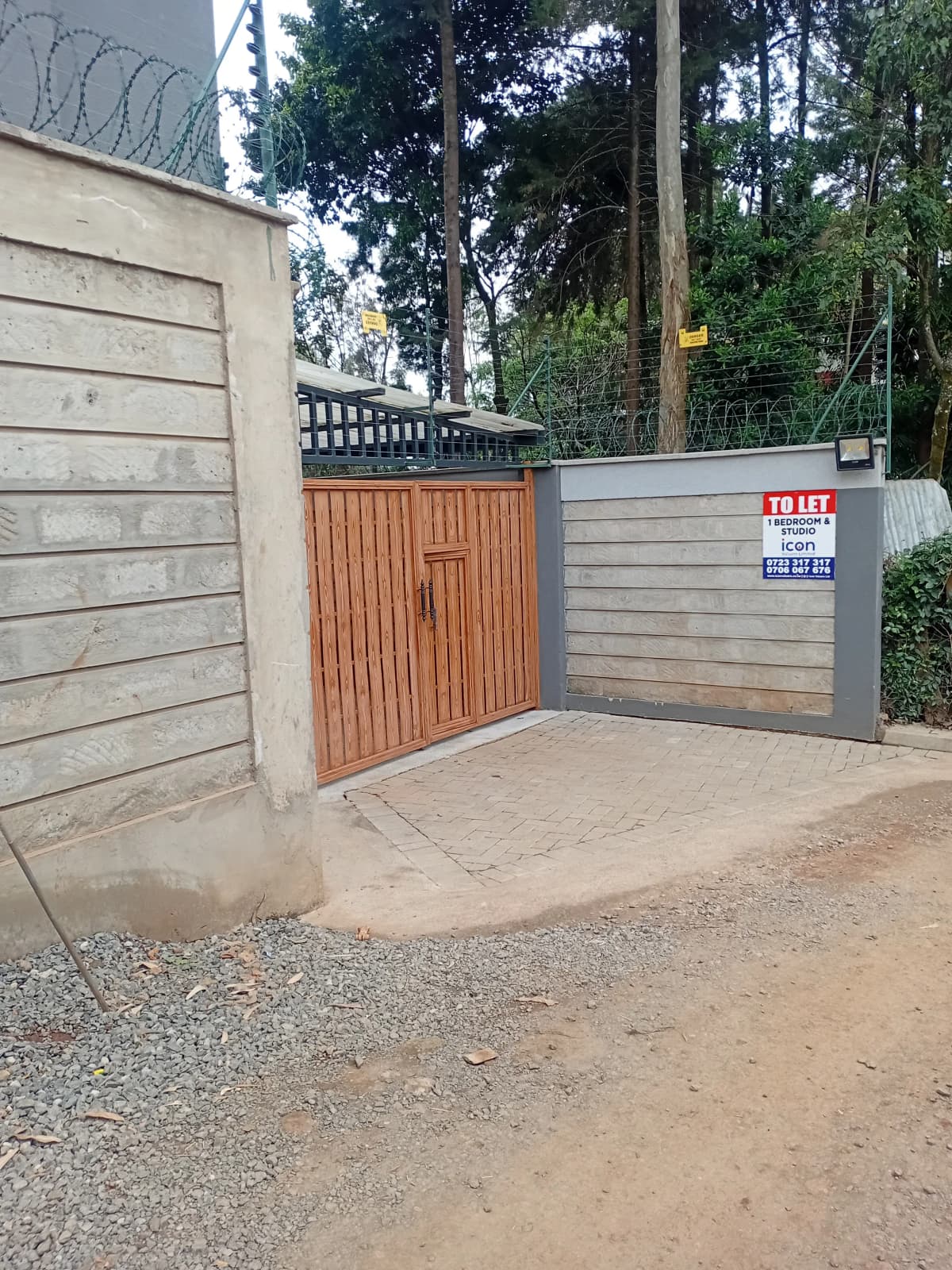 Gated compound entrance with wooden gate and security wall
