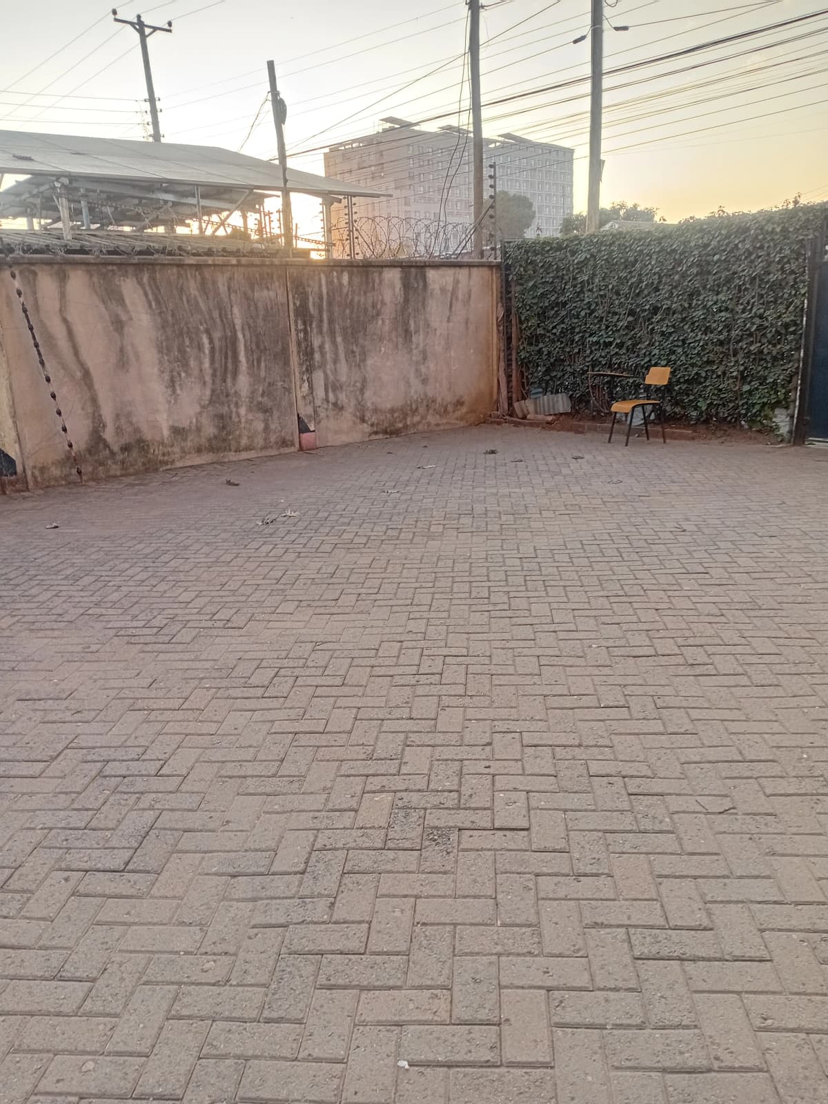 Paved compound courtyard with rusted metal gate and hedging