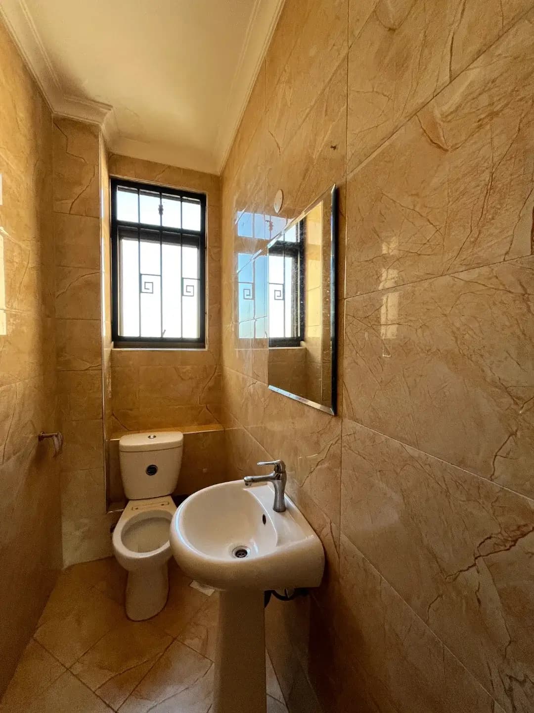 Compact bathroom with toilet, wall-mounted sink, tiled walls