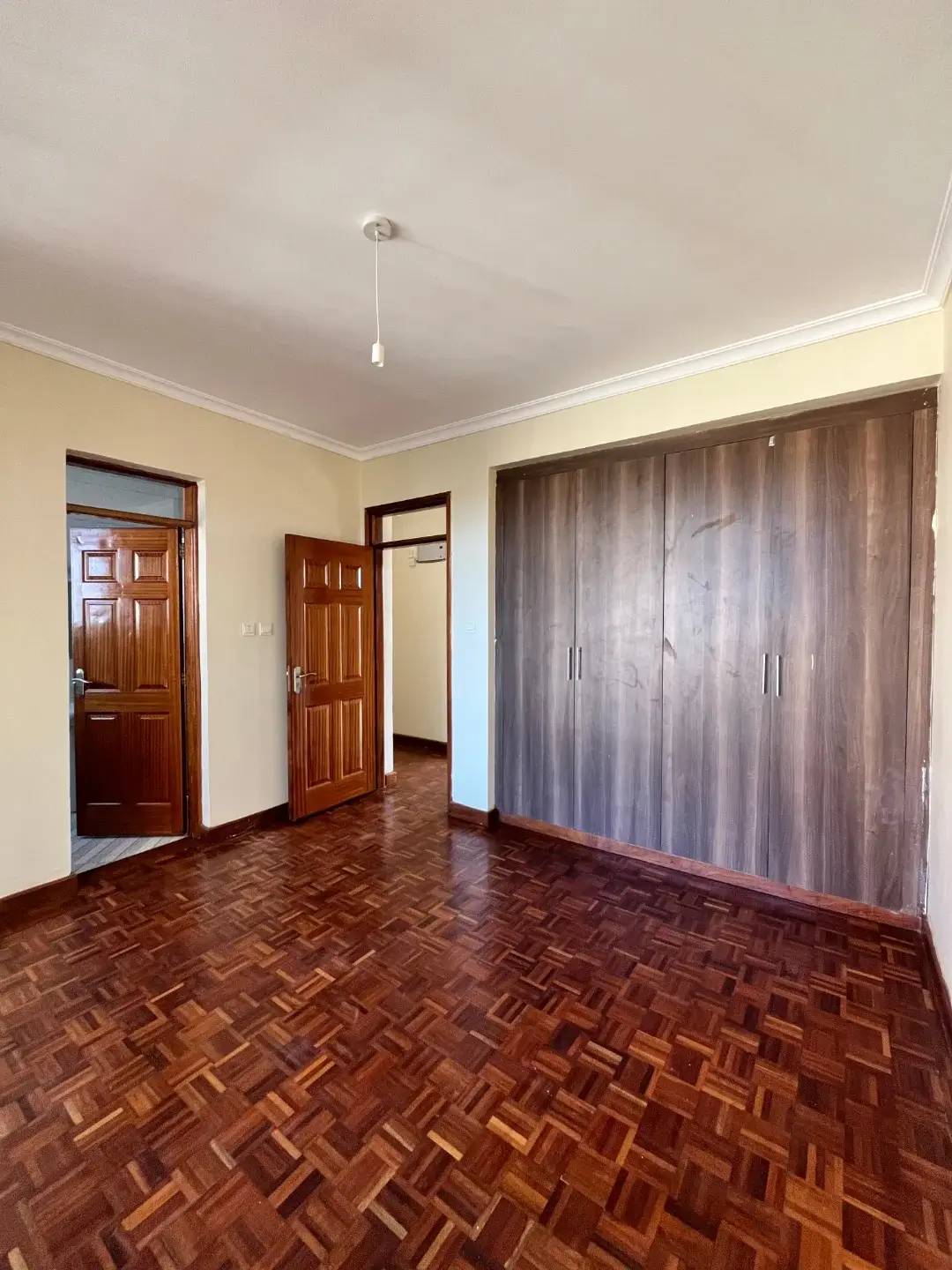 Spacious bedroom with herringbone wood flooring and built-in wardrobes