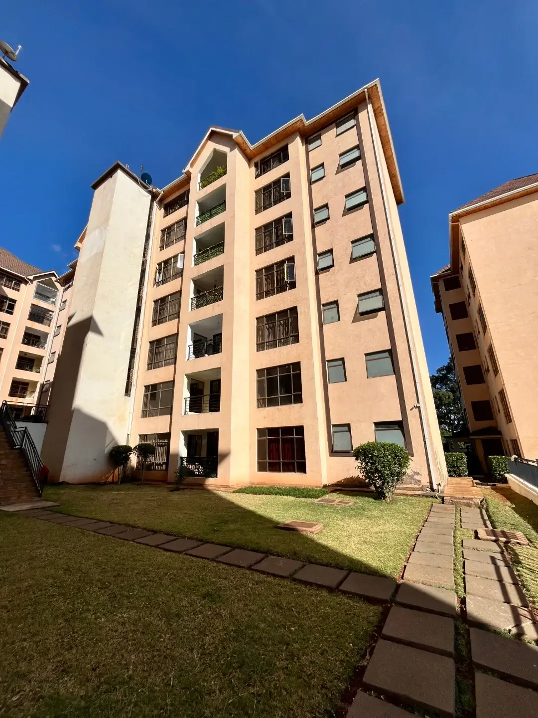 Multi-story residential building with manicured lawn and pathway