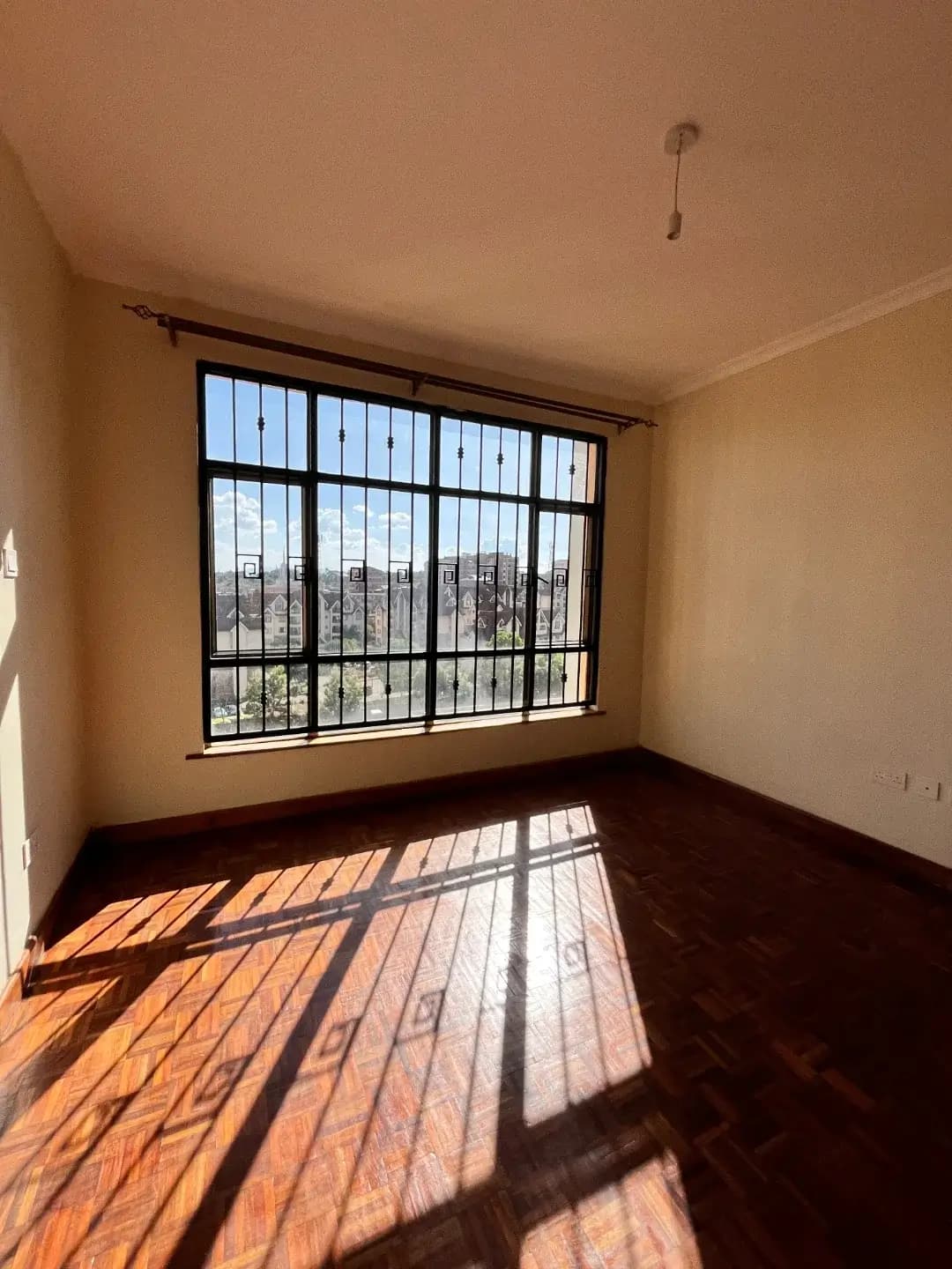 Bright bedroom with large barred window overlooking cityscape