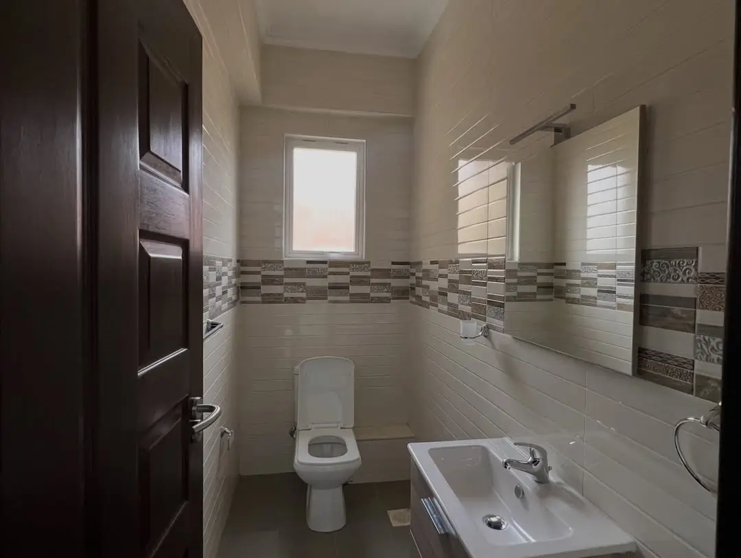 Modern bathroom with toilet, sink, and decorative tile border