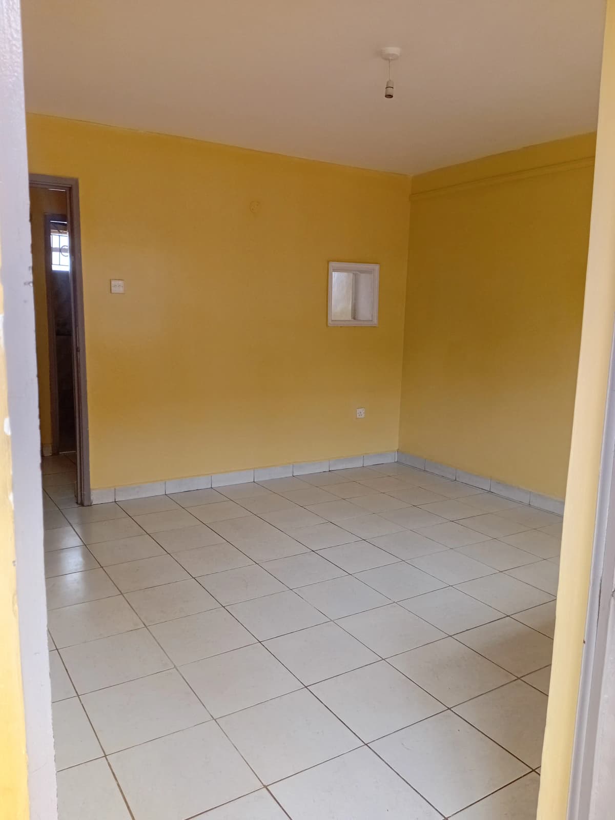 Bright yellow-walled room with tiled floor, minimal furnishings
