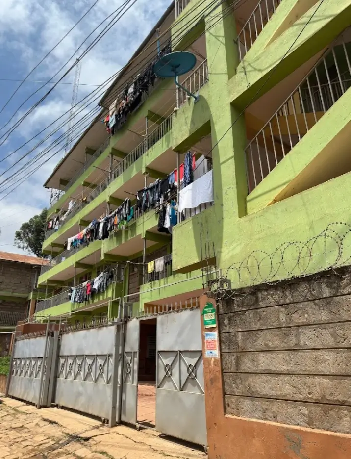 Multi-story residential building with yellow facade and metal gates