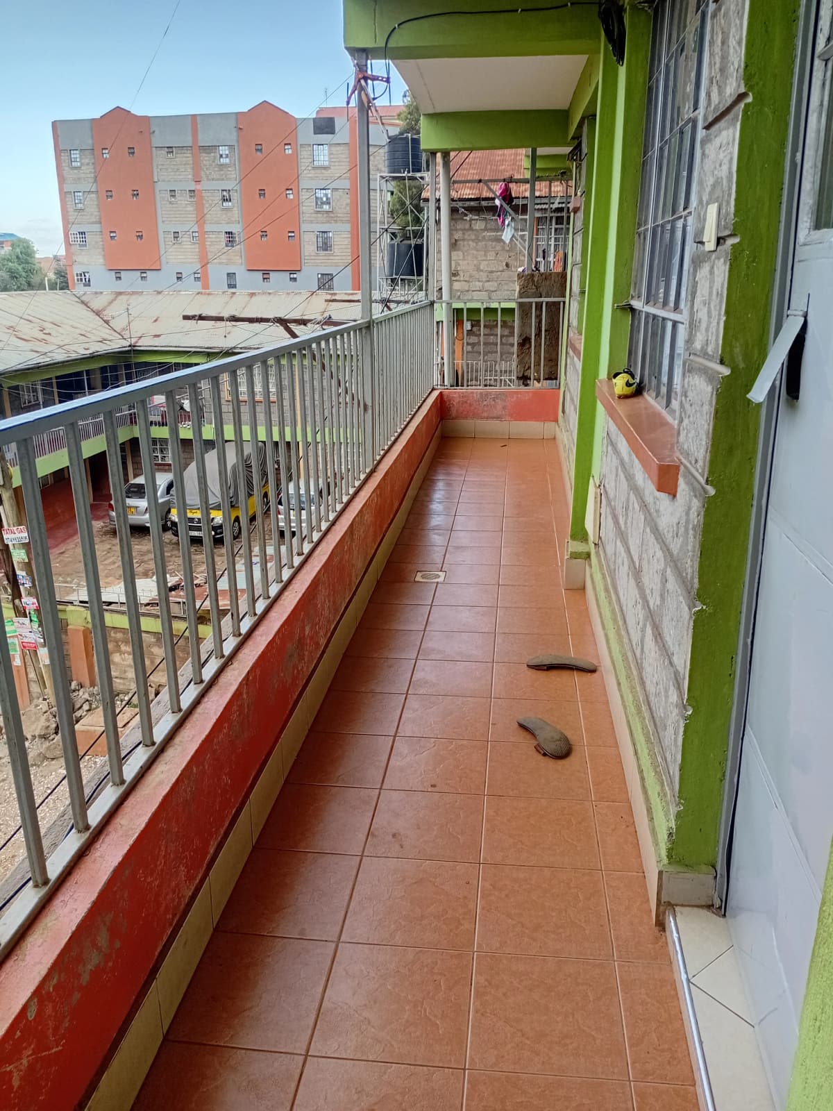 Long narrow balcony with terracotta tiles and green wall trim