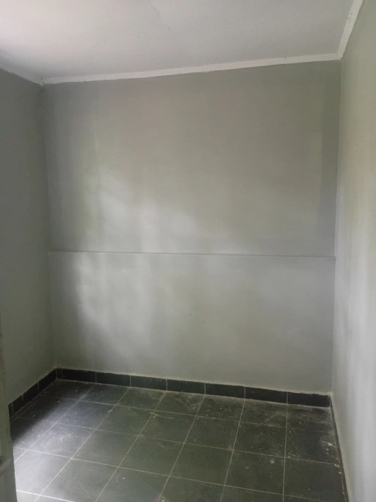 Empty storage room with tiled floor and plain walls