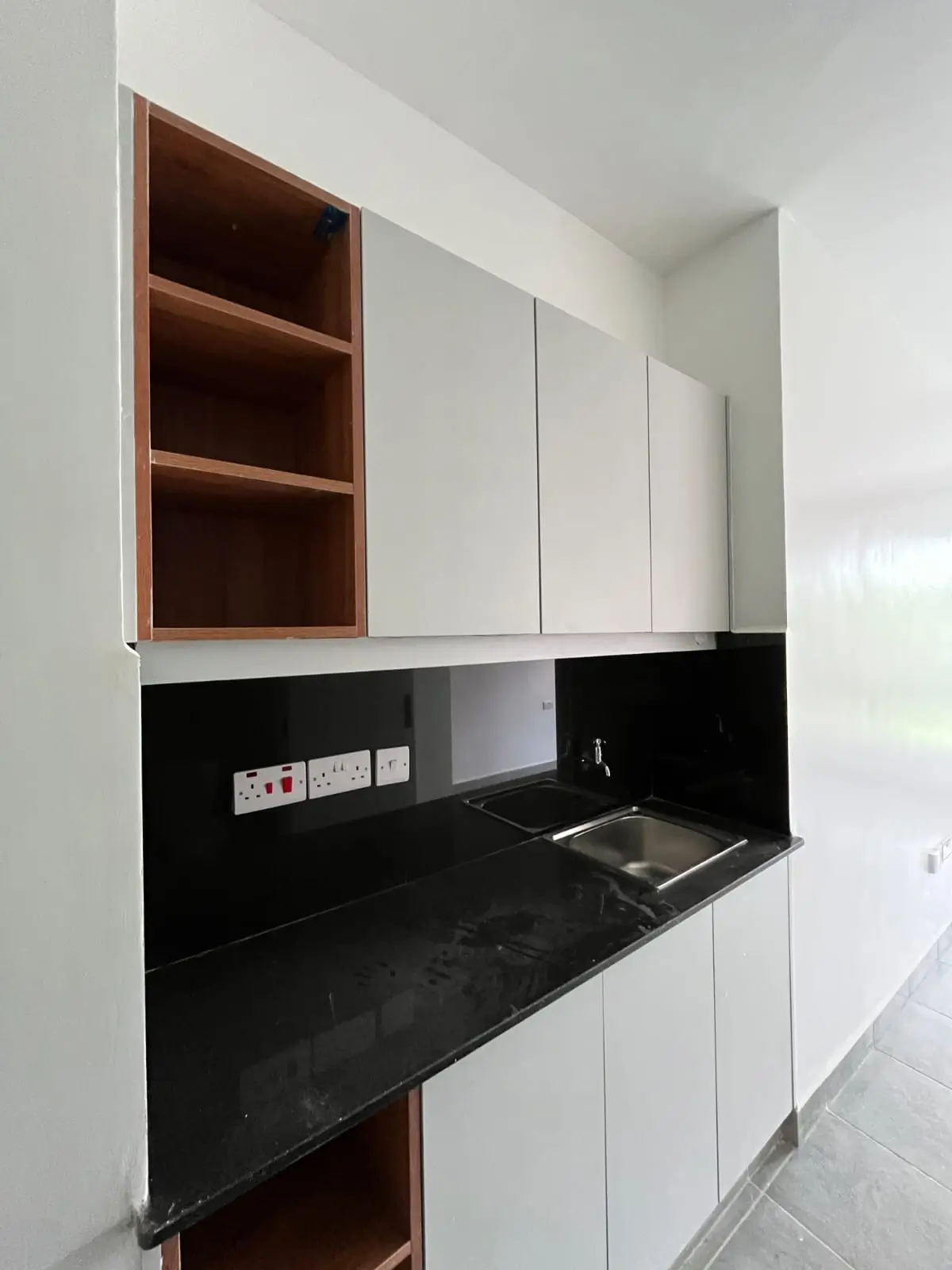 Modern kitchen with black countertop, white cabinetry, wooden shelves