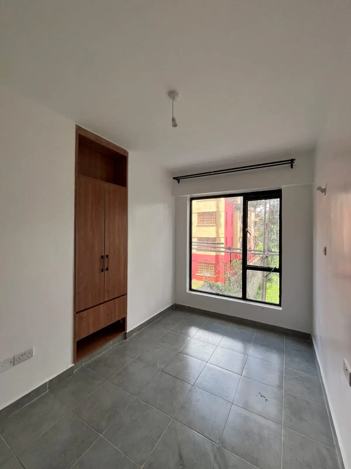 Bright bedroom with dark wood wardrobe and window views