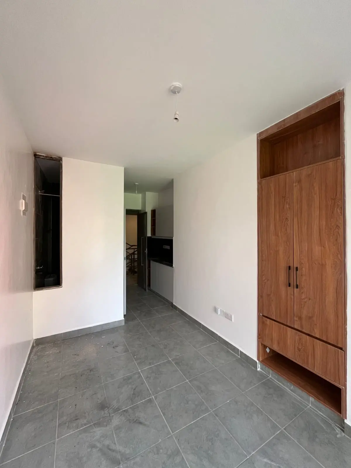 Bright hallway with grey tile flooring and wooden wardrobe
